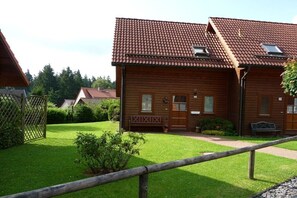 A wooden cabin with a tiled roof, a small porch, and a fenced yard. - Holiday home with 2 bedrooms (Hasselfelde-Rotacker)