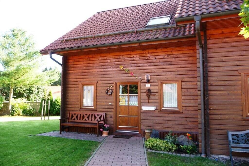 Une cabane en bois avec un toit en tuiles, une porte d’entrée et un banc à l’extérieur.