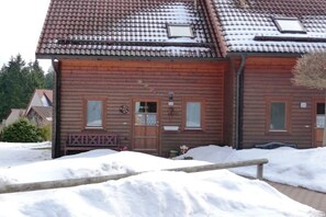 Ein Holzhaus mit Ziegeldach und einer Veranda, der Boden ist mit Schnee bedeckt.
