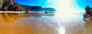 Ein Strand mit klarem Wasser, felsigen Klippen und einem ruhigen Meer.