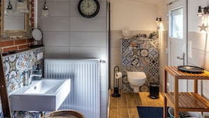 Ein Badezimmer mit Waschbecken, Toilette, Heizkörper und einer Wandverzierung.