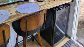 Une cuisine compacte avec un plan de travail en bois, une bouilloire noire, une machine à café et un réfrigérateur.