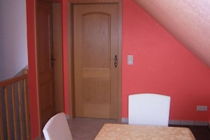 A room with a wooden door, a white chair, and a table. - Holiday home in Dambeck with swimming pool (Dambeck)