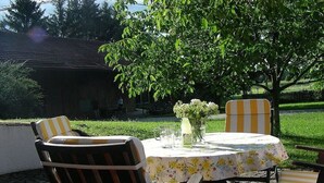 Un espacio al aire libre con una mesa, sillas, un florero y una botella.