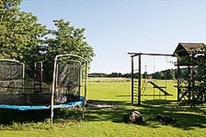Un trampolín en una zona verde con una estructura metálica y un edificio al fondo.
