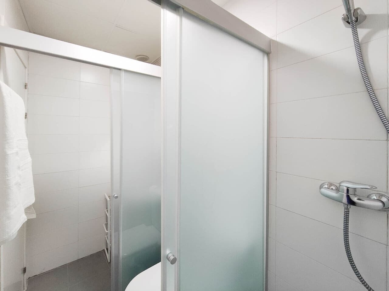 Ein modernes Badezimmer mit einer Duschkabine aus Glas, einer Handbrause und einem Handtuchhalter.