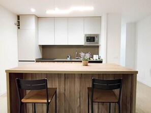 Una cucina moderna con un'isola in legno, due sedie, un forno a microonde e un lavello.