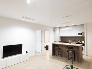 Una cucina moderna con schermo piatto, forno a microonde e un angolo bar con sgabelli.