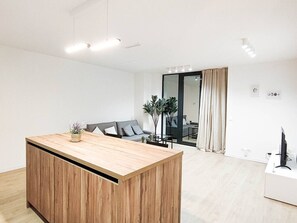 Un soggiorno moderno con isola in legno, un divano grigio e un'area pranzo con tavolo e sedie.