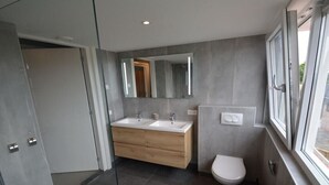A modern bathroom with two sinks, a toilet, and a large mirror. - Holiday apartment with 1 bedroom (Serooskerke)