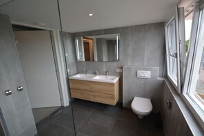 Ein modernes Badezimmer mit zwei Waschbecken, einer Toilette und einem großen Spiegel.