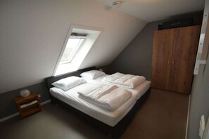 Ein Schlafzimmer mit einem Bett, einem Fenster, einem Kleiderschrank und einem kleinen Nachttisch.