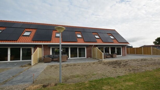 A modern house with a red-tiled roof, solar panels, and a covered patio area. - Holiday apartment with 1 bedroom (Serooskerke)