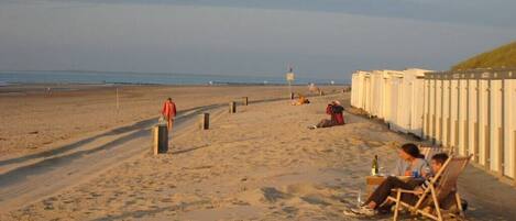 A beach with a wooden fence, a lifeguard tower, and people relaxing.