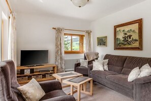 Een woonkamer met een televisie, bank en salontafel.
