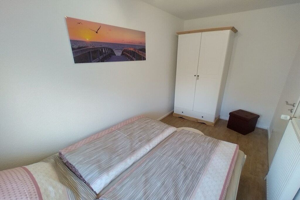 Ein Schlafzimmer mit einem Bett, einem Kleiderschrank, einer Heizung und einem Bild an der Wand.