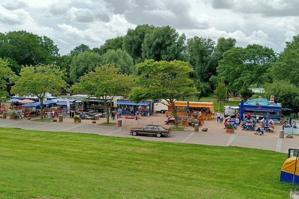 A park with picnic areas, food stalls, and a bus.