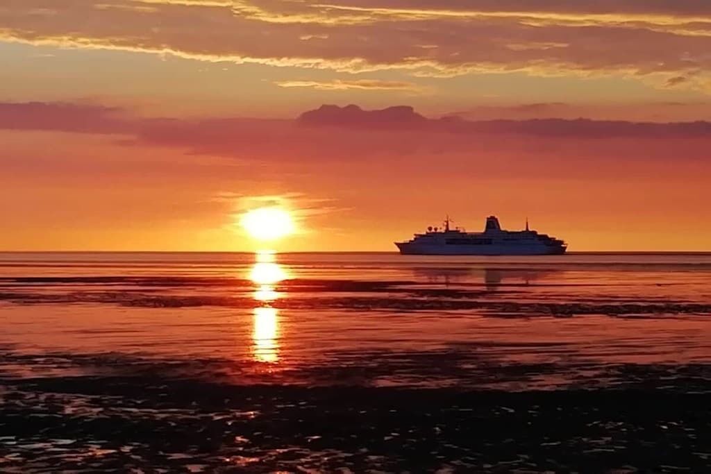Un navire au coucher du soleil, avec un ciel dégagé.