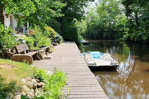 A wooden dock extending into a calm river, with a boat docked at the end. - Holiday home in the North Sea with 4 bedrooms (Neuenkirchen)