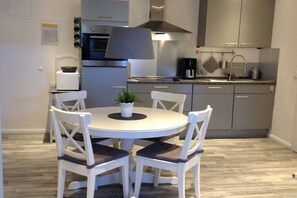 Una cucina compatta con un tavolo rotondo, sedie, una macchina per il caffè e un fornello.
