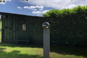 En rustik träbyggnad med en bänk och ett sfäriskt föremål på en piedestal.
