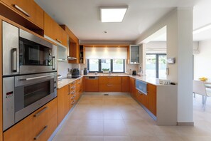 A modern kitchen with stainless steel appliances, wooden cabinets, and a central island. - The Heli House | Private Pool, Movie Theater, Gym & Games (Viseu)