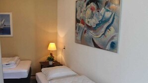Quarto com uma cama, mesa de cabeceira com abajur e um quadro na parede.