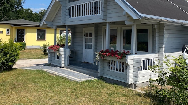 A two-story house with a front porch, a balcony, and a small garden area.