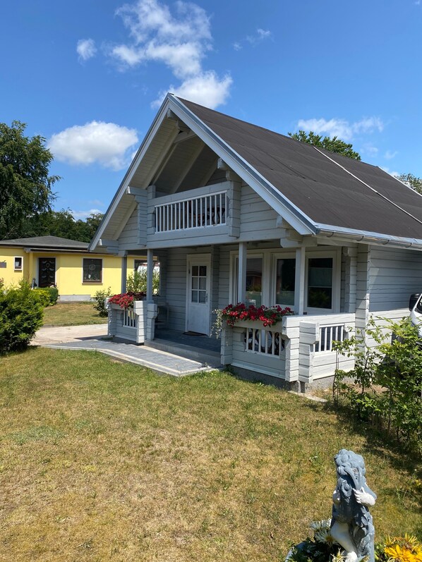 A two-story house with a front porch, a balcony, and a small garden area.