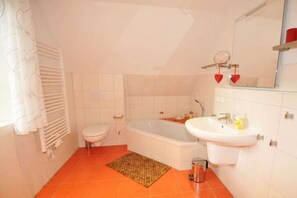 A bathroom with a white toilet, a bathtub, a sink, and a mirror. - Holiday home with 2 bedrooms (St.Peter-Ording)