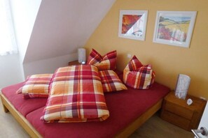 A bed with plaid bedding, a nightstand with a lamp, and two framed pictures on the wall. - Holiday home with 2 bedrooms (St.Peter-Ording)