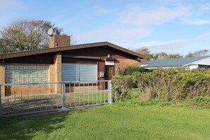 Un bâtiment d’un seul étage, doté d’un garage, d’une clôture en métal et d’une cour gazonnée.