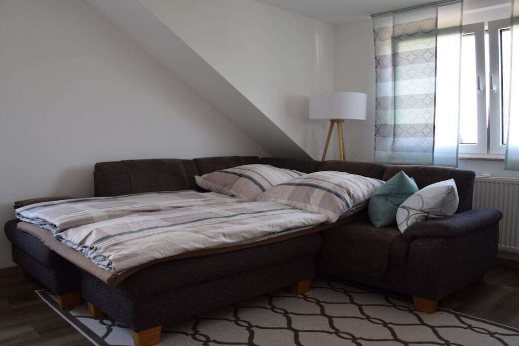 A bedroom with a bed, a nightstand, a lamp, and a window with curtains.