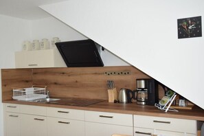 Een keuken met een houten aanrecht, een spoelbak, een koffiezetapparaat en een klok aan de muur.