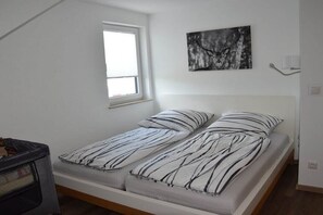 A small, single-bed room with a window, a wall-mounted artwork, and a bedside table. - Holiday apartment Mia (Künzell)