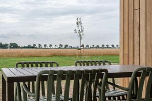 A table and chairs set outdoors with a view of a field and trees in the background. - Holiday home with 1 bedroom (Zonnemaire)