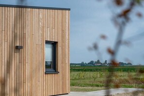 A modern building with a wooden exterior and a window. - Holiday home with 1 bedroom (Zonnemaire)