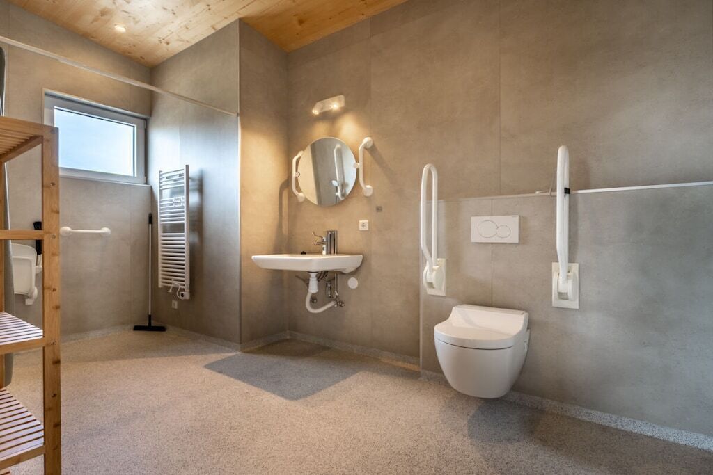 A modern bathroom with a sink, mirror, toilet, and towel rack.