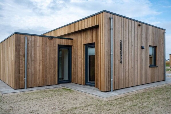 A modern building with a wooden exterior, large windows, and a flat roof. - Holiday home with 1 bedroom (Zonnemaire)