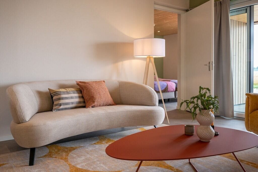 Een moderne woonkamer met een bank, een salontafel, een vloerlamp en een potplant.
