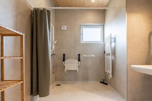 A small bathroom with a shower, a toilet, a window, and a towel rack. - Holiday home with 1 bedroom (Zonnemaire)
