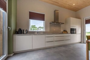 Ett modernt kök med ett stort fönster, inbyggda vitvaror och en minimalistisk design.