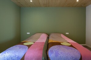Ein Zimmer mit zwei Betten, jedes mit einer farbenfrohen Tagesdecke.