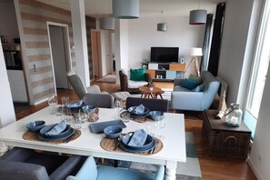 A modern living room with a dining area, a television, and a cozy seating arrangement. - Holiday apartment with 1 bedroom (Heiligenhafen)