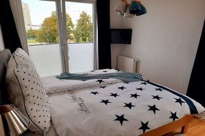 A bedroom with a bed, a window, a television, and a lamp. - Holiday apartment with 1 bedroom (Heiligenhafen)