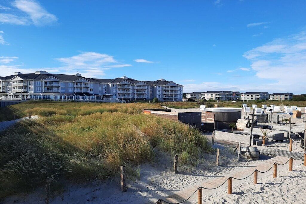 Ein Strandhotel mit mehrstöckigen Gebäuden, einer Sandstrandfläche und einer Holzpromenade.