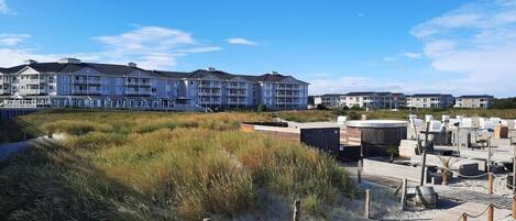 Ein Strandhotel mit mehrstöckigen Gebäuden, einer Sandstrandfläche und einer Holzpromenade.