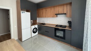 Cocina moderna con lavadora integrada, horno y lavaplatos, paredes grises y armarios de madera.