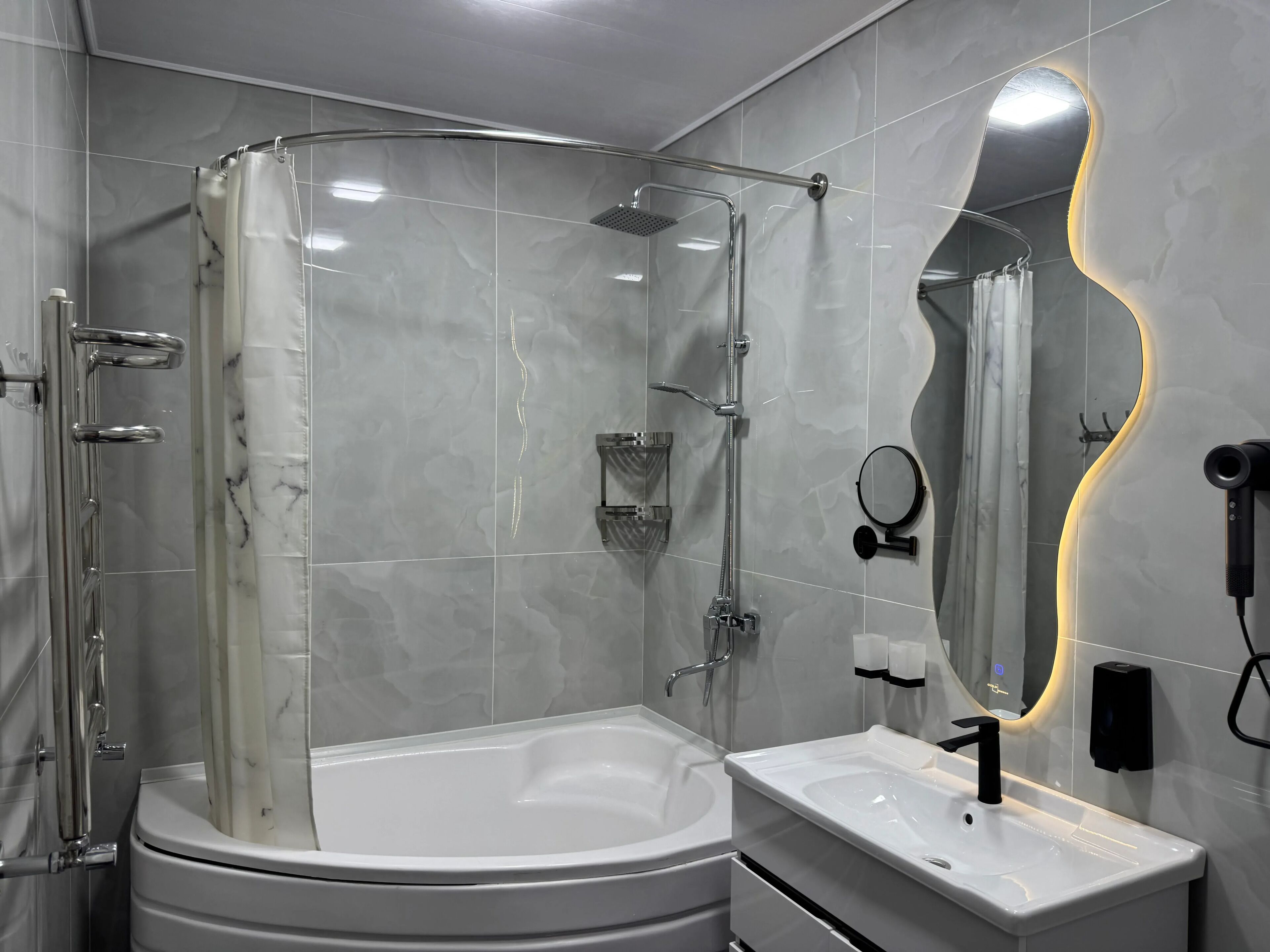 Un bagno moderno con doccia vetrata, una vasca da bagno bianca e un mobile lavabo con specchio.