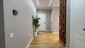 Un pasillo con piso de madera, paredes blancas y una planta en maceta.